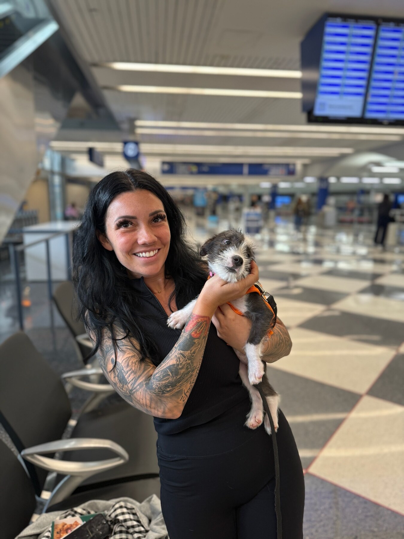 A flight nanny holding a small dog inside an airport